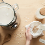 Top-down flat lay of homemade oat milk being strained into a glass bottle.